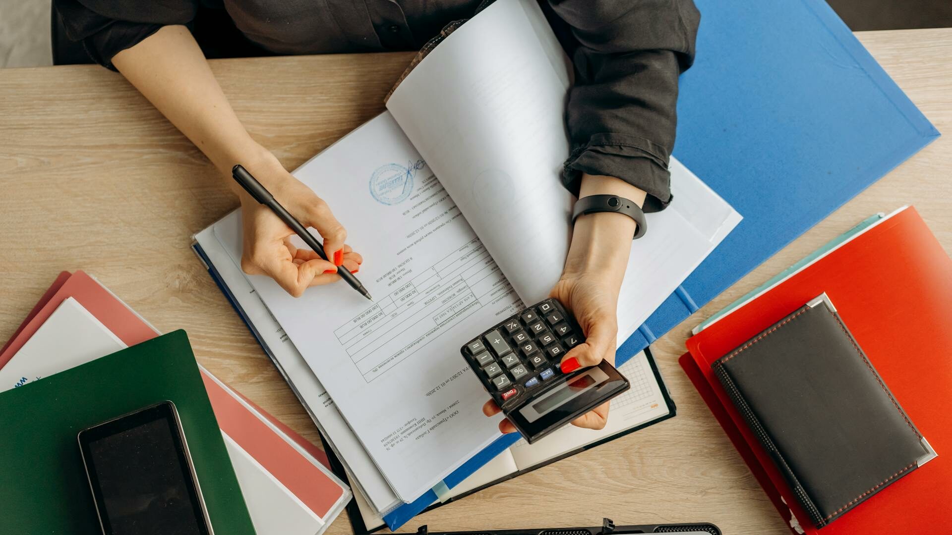 pexels-mikhail-nilov-8296970 Piles de dossiers alignés sur une table en bois contre un mur blanc