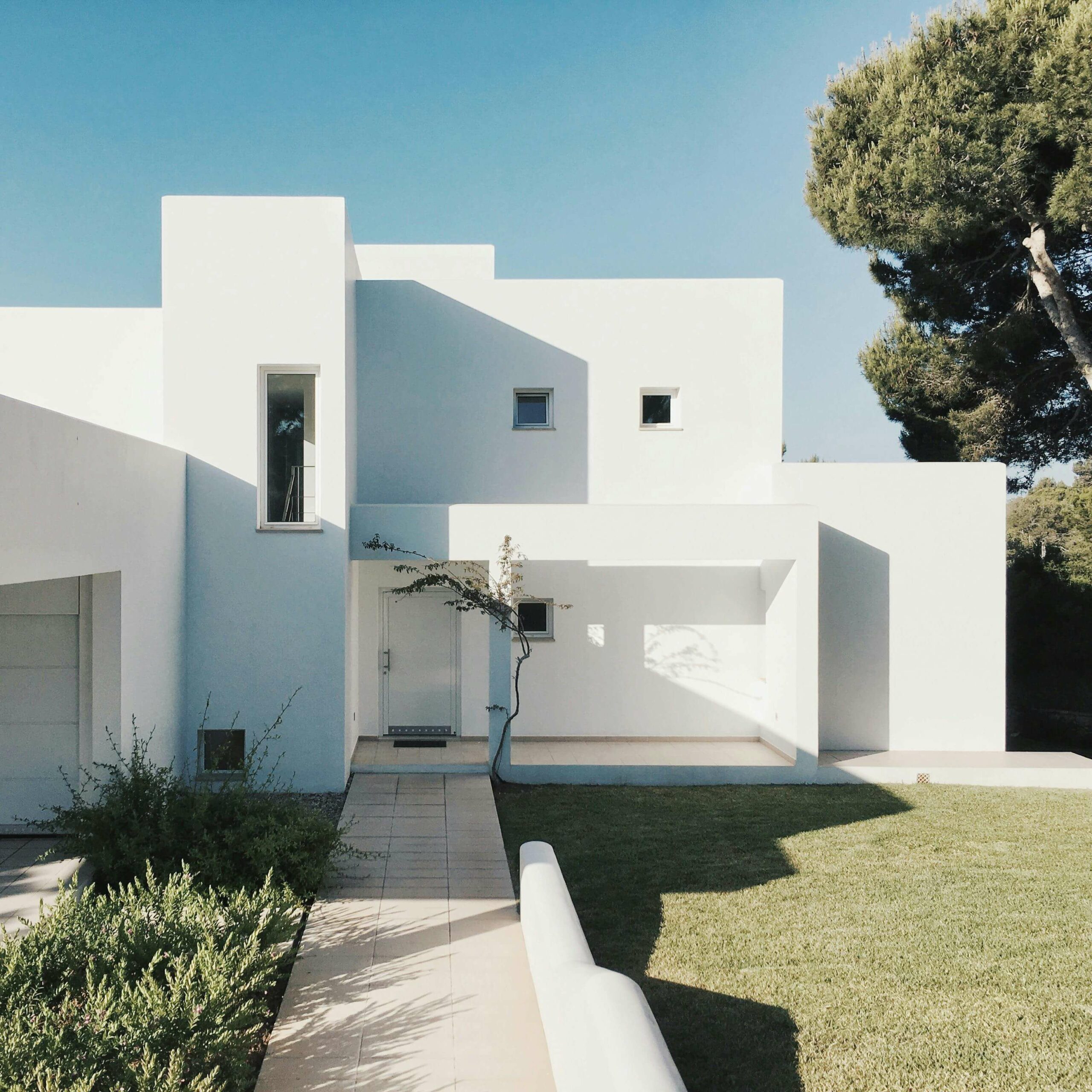 Architecture moderne et épurée au cœur de la nature Maison contemporaine blanche au design minimaliste, entourée de verdure et baignée de lumière naturelle.